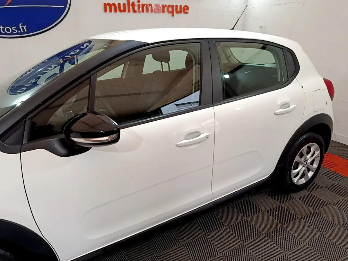 Profil côté gauche d'une Citroën C3 blanche de 2019 avec rétroviseur noir et poignées de porte ton caisse.
