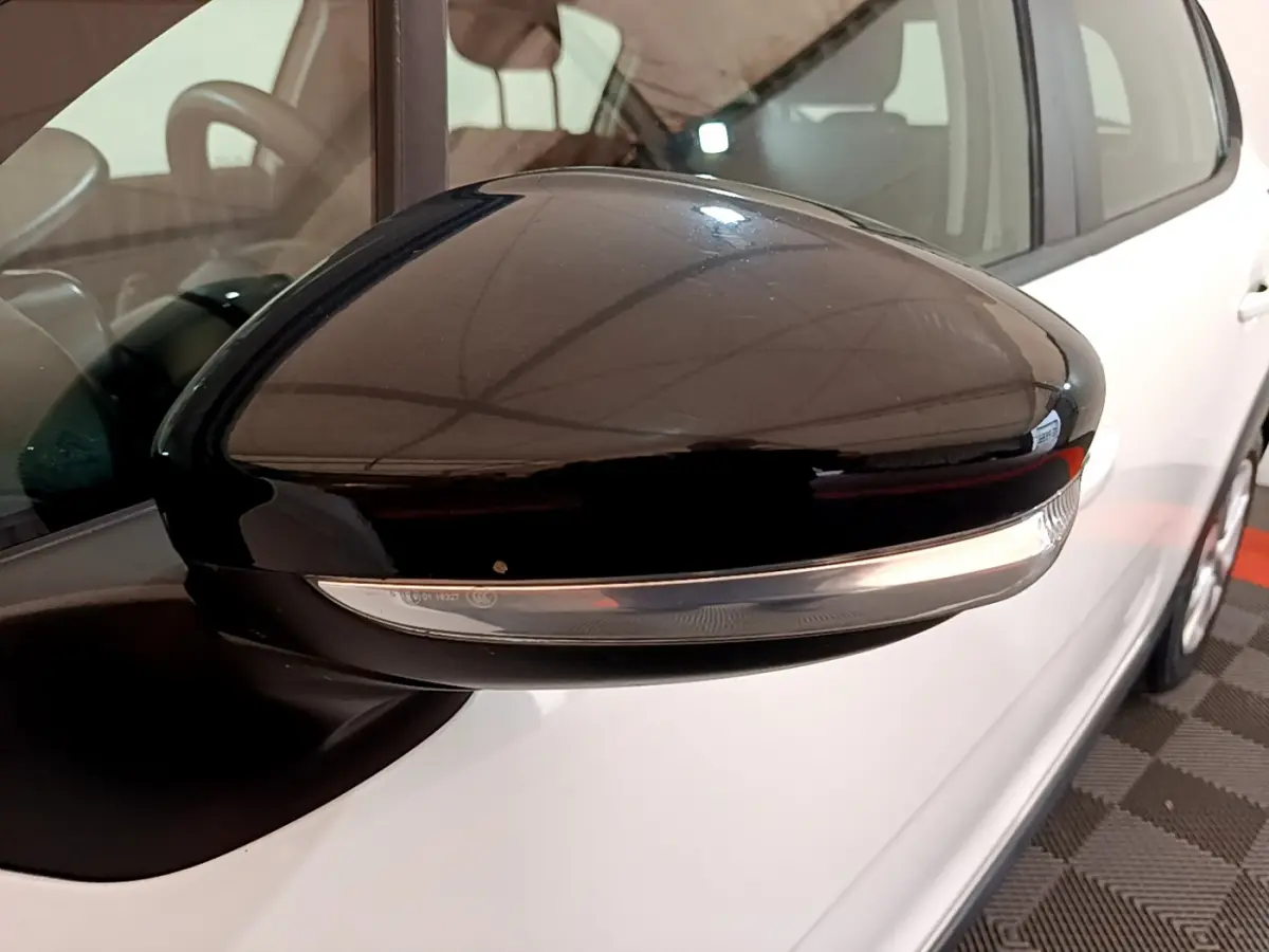 Rétroviseur noir avec clignotant intégré côté gauche d'une Citroën C3 blanche vue de près en intérieur.