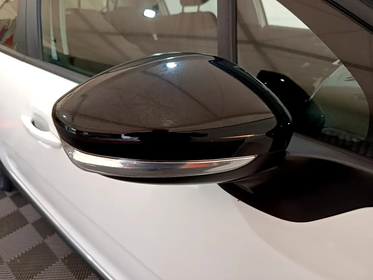 Rétroviseur noir brillant côté gauche d'une Citroën C3 blanche de 2019, avec clignotant intégré.