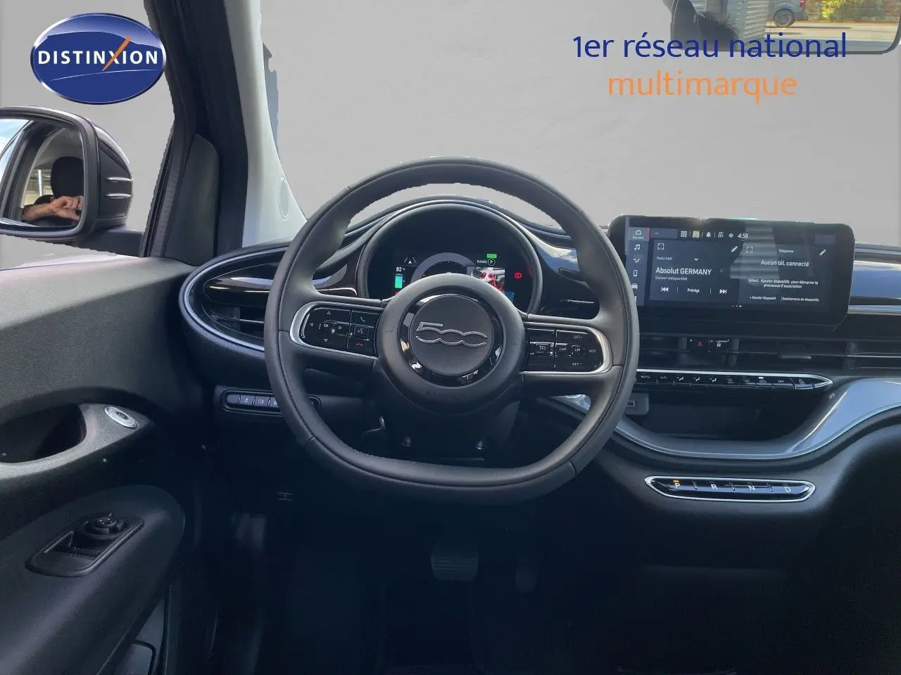 Vue intérieure centrée sur le volant noir et le tableau de bord digital de la Fiat 500 électrique 2023.