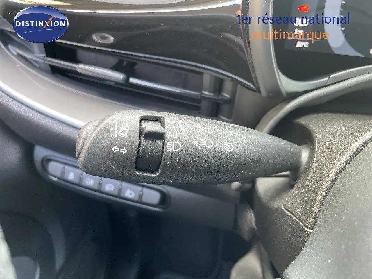 Gros plan sur la commande des feux et clignotants côté gauche du tableau de bord d'une Fiat 500 électrique noire 2023.