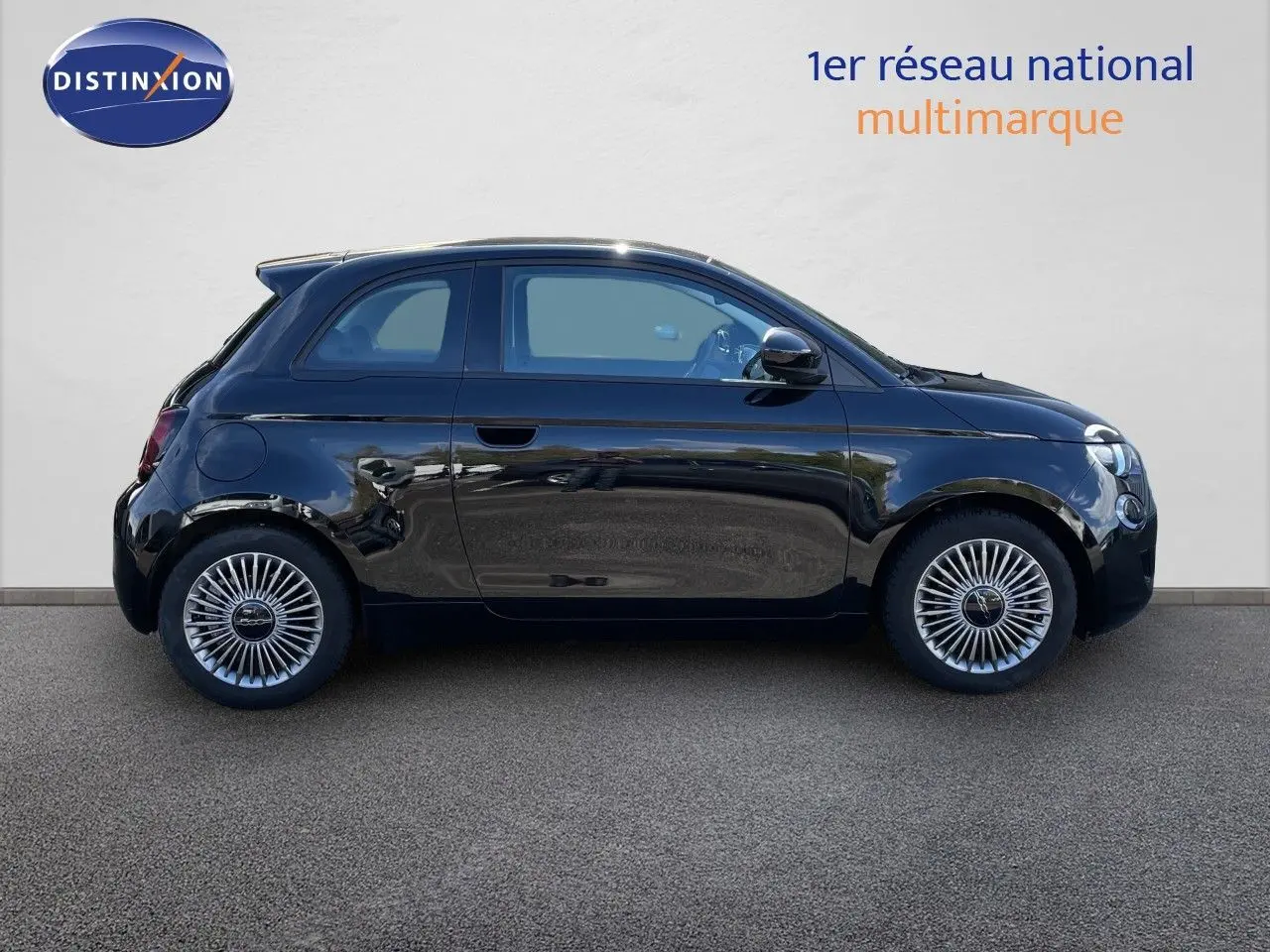 Profil côté gauche de la Fiat 500 électrique noire 2023 avec jantes spécifiques et lignes compactes urbaines.