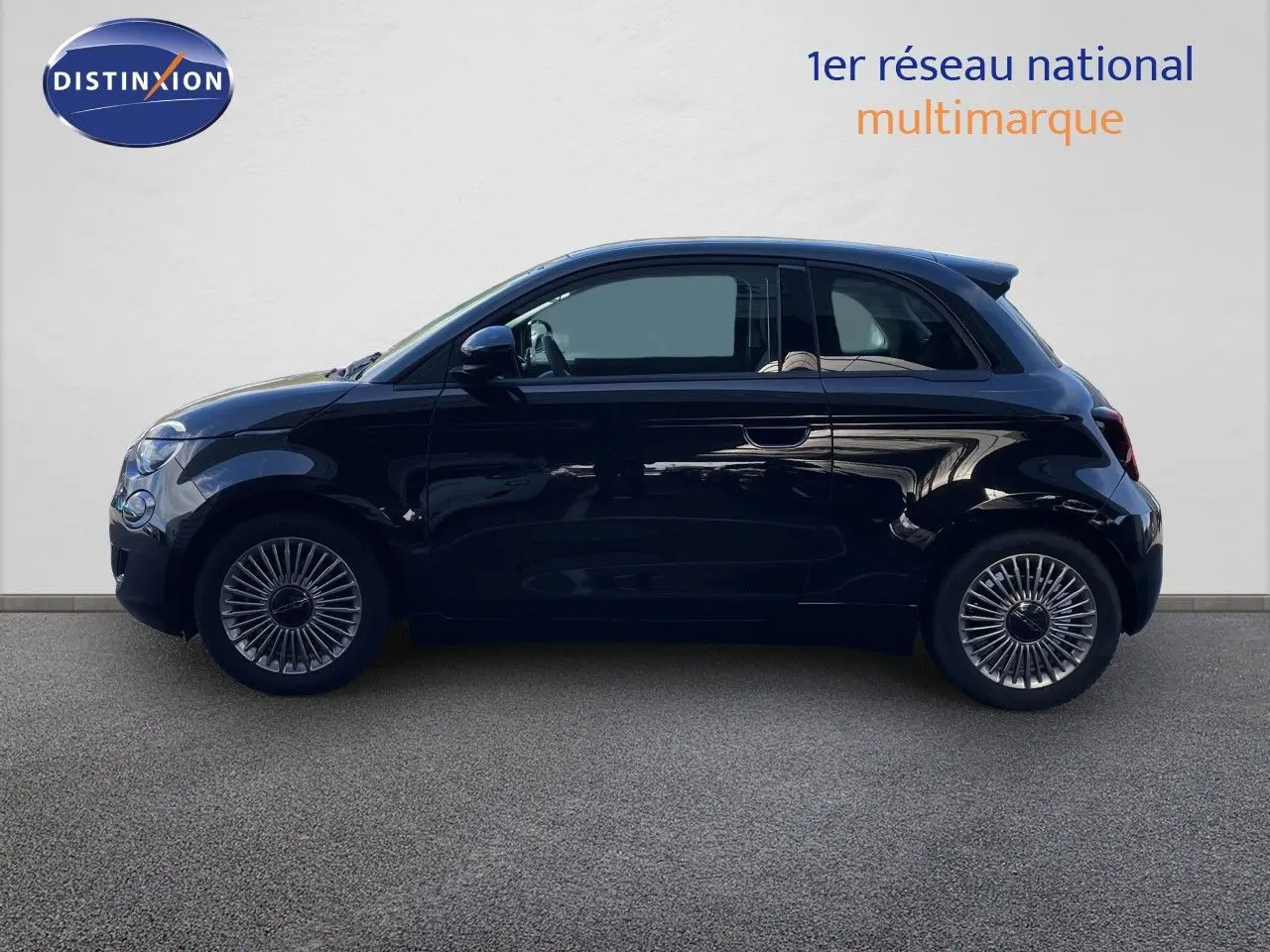 Profil côté gauche d'une Fiat 500 électrique noire 2023, avec jantes stylisées et lignes compactes urbaines.