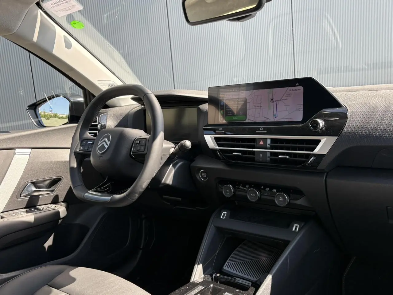 Vue intérieure côté conducteur de la Citroën C4 Hybrid 145 e-DSC6 Max avec tableau de bord noir et écran tactile GPS.