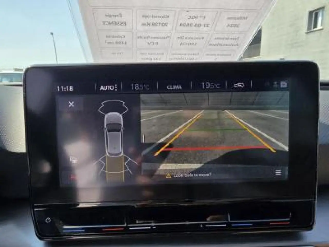 Écran tactile central montrant la caméra de recul et l'aide au stationnement d'une SEAT Leon blanc Nevada, vue intérieure avant.