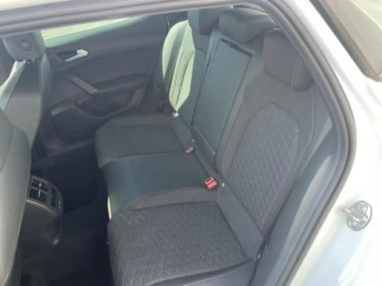 Vue intérieure côté droit sur la banquette arrière noire avec surpiqûres rouges d'une SEAT LEON IV Blanc Nevada 2024.