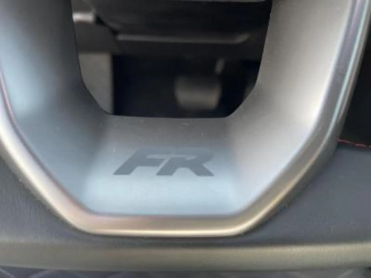 Gros plan sur le volant avec logo FR de la SEAT LEON IV blanc Nevada, mettant en valeur la finition sportive.