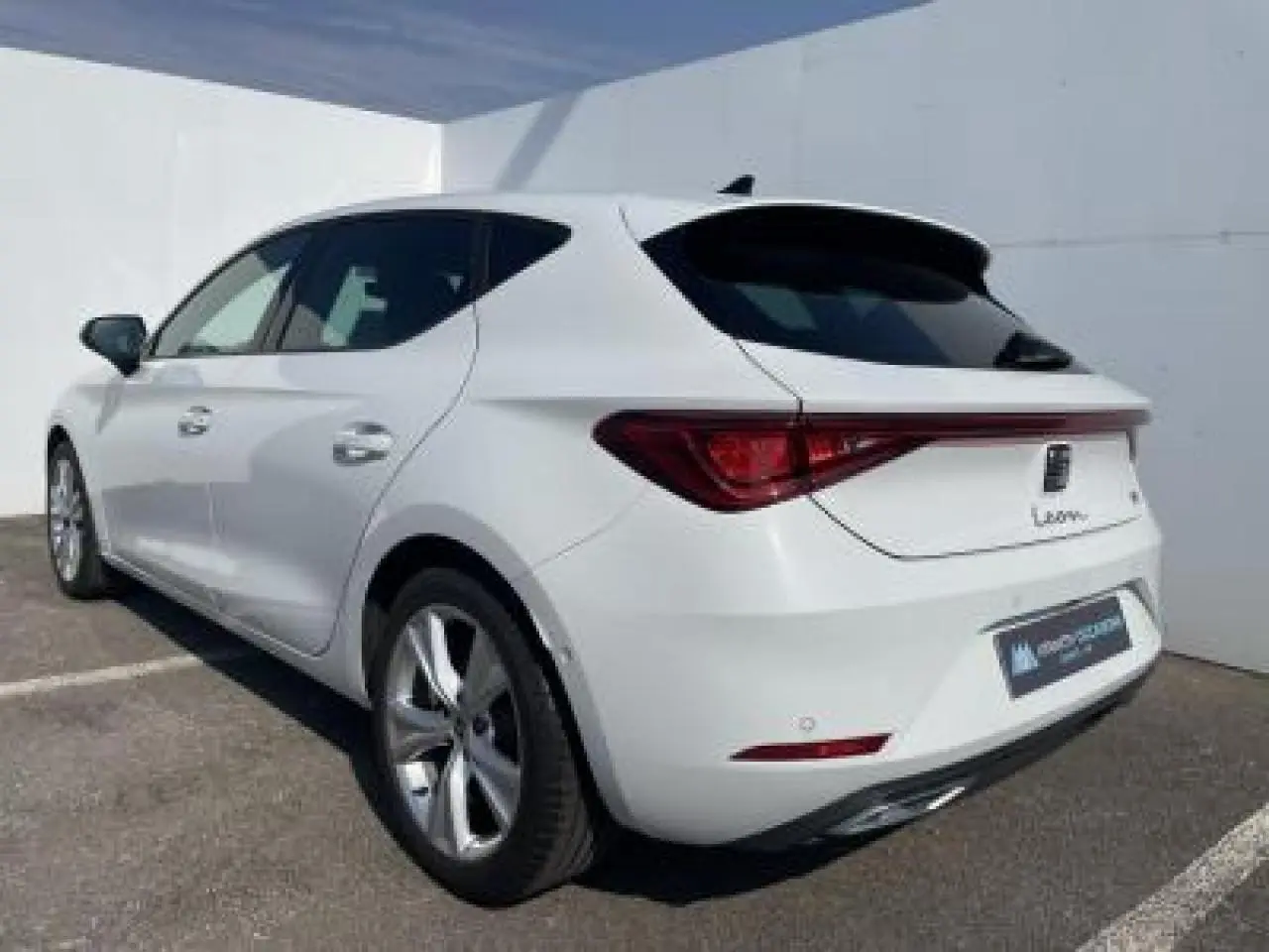SEAT Leon blanc Nevada vue 3/4 arrière droit, jantes alliage 17 pouces et vitres arrière surteintées.