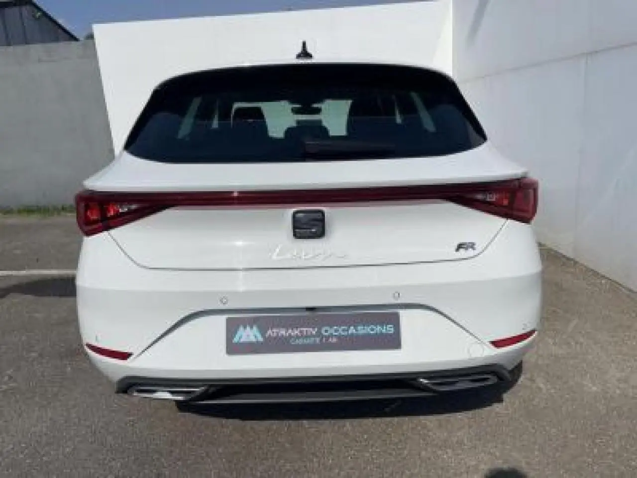 Vue arrière d'une SEAT Leon IV blanche Nevada avec logo FR et feux arrière reliés par une bande lumineuse rouge.