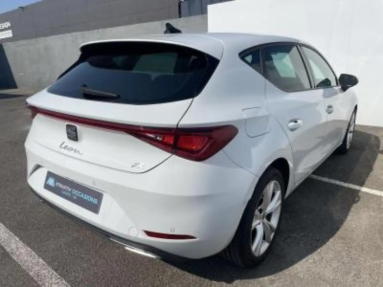 SEAT Leon blanc Nevada vue 3/4 arrière droit, avec feux arrière reliés et jantes alliage 17 pouces.