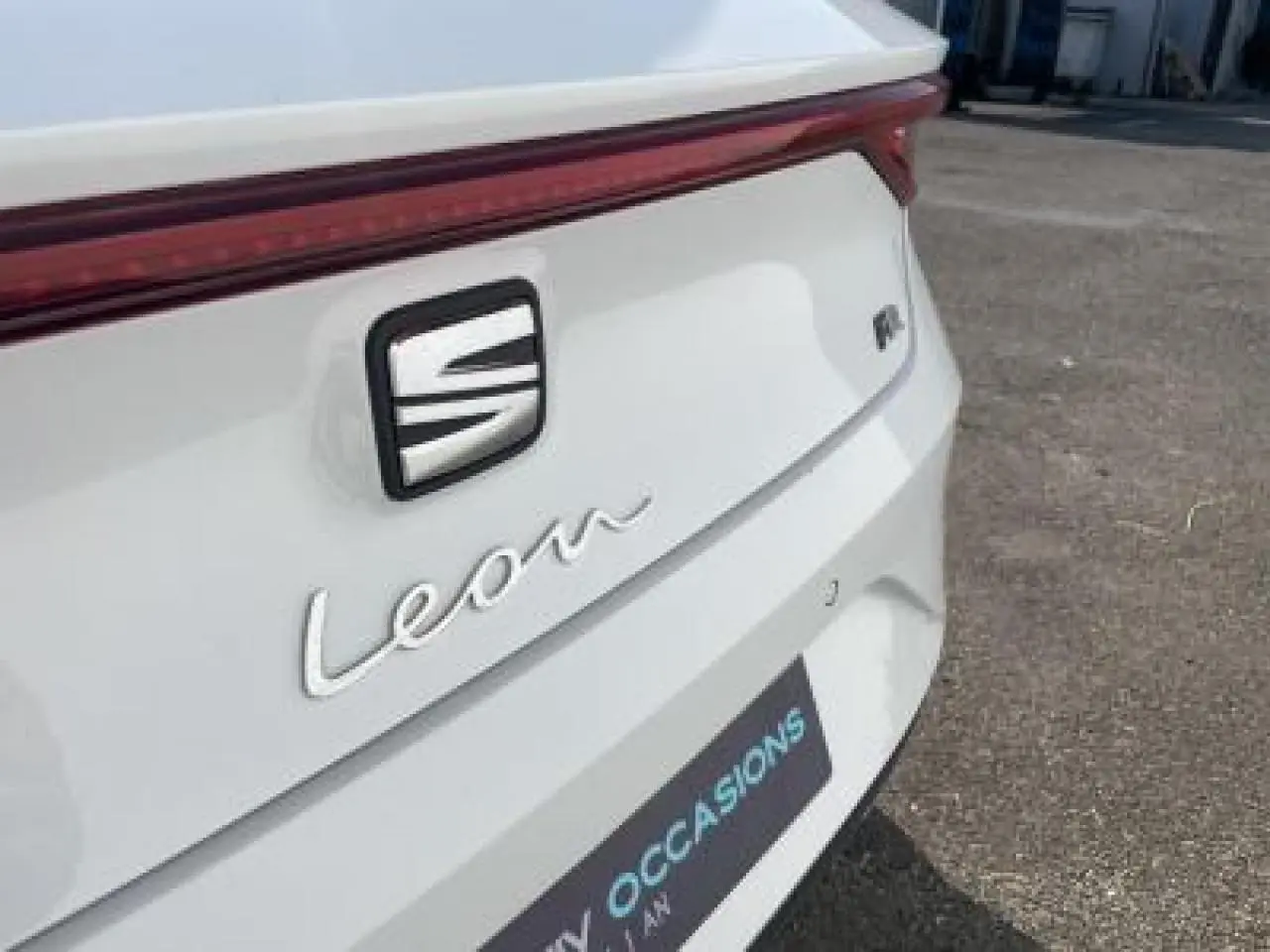 Gros plan sur l'arrière blanc Nevada d'une SEAT Leon IV avec logo et feu arrière continu lumineux rouge.