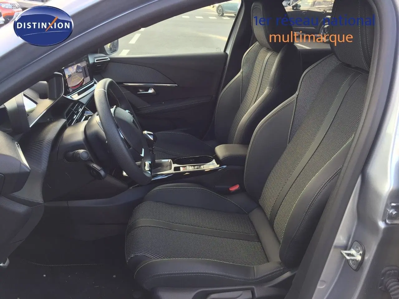 Vue intérieure côté conducteur d'une Peugeot 208 2025 gris Artense, sièges en cuir noir et tableau de bord moderne.