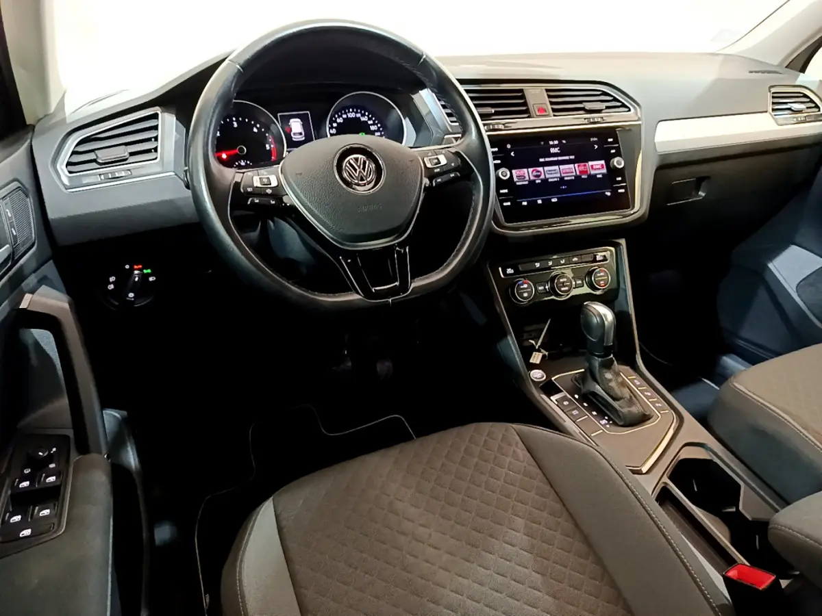 Vue intérieure du tableau de bord et volant cuir noir du Volkswagen Tiguan gris clair avec écran tactile central.