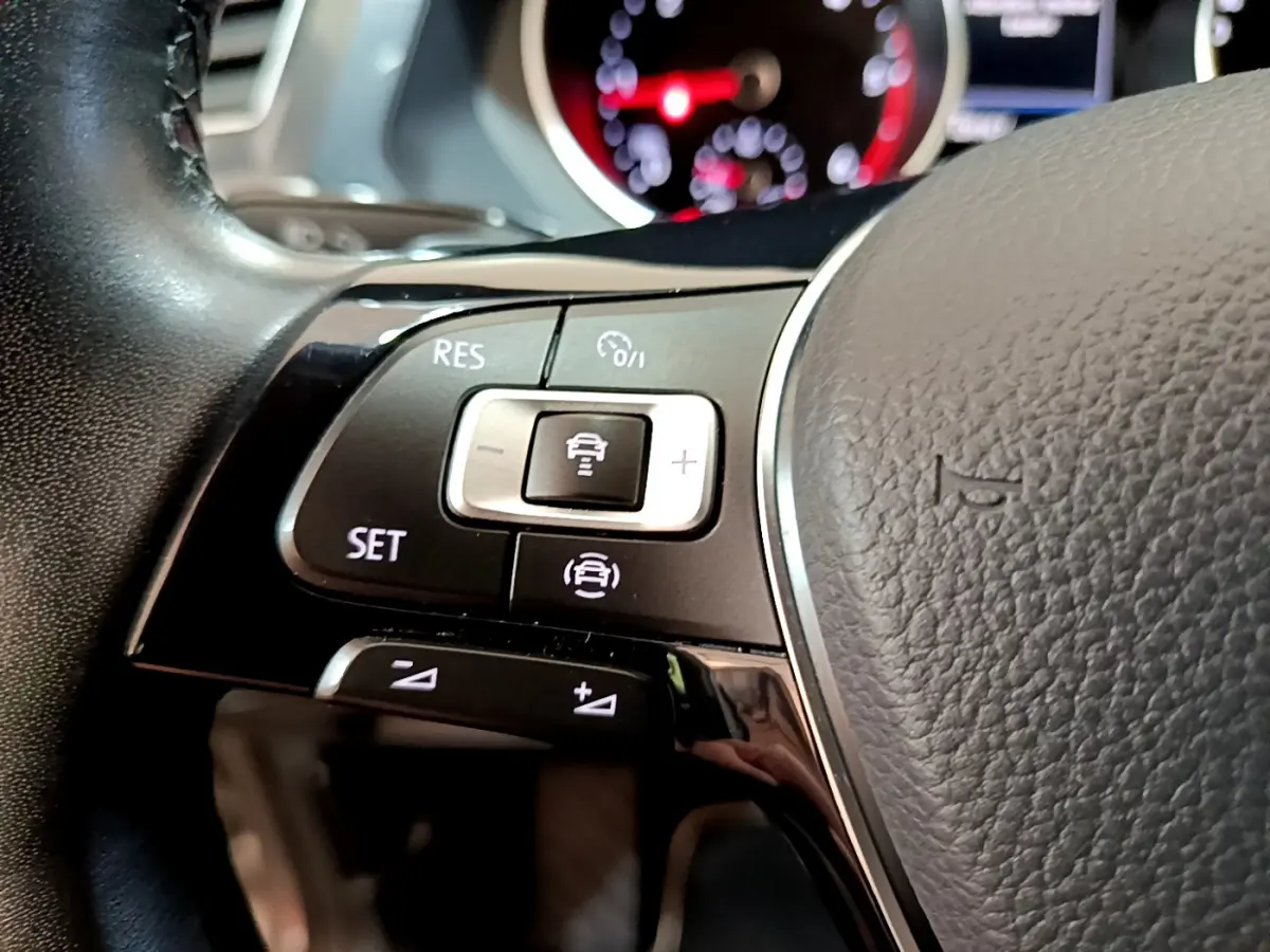 Gros plan sur les commandes de régulateur de vitesse au volant cuir noir du Volkswagen Tiguan 2020.