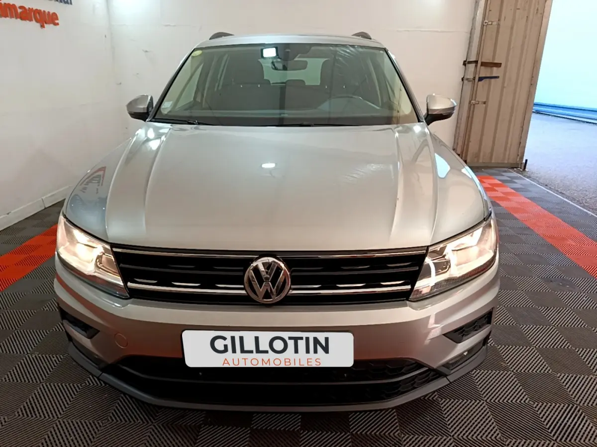 Vue frontale d'un Volkswagen Tiguan gris clair 2020 avec phares allumés et calandre noire brillante.