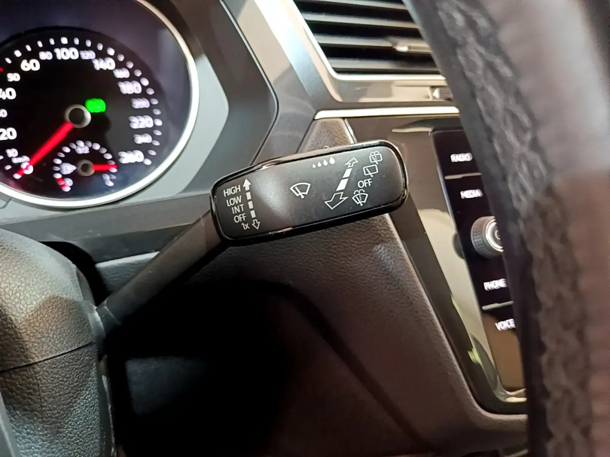 Gros plan sur la commande d'essuie-glace à gauche du volant dans l'habitacle du Volkswagen Tiguan gris clair 2020.