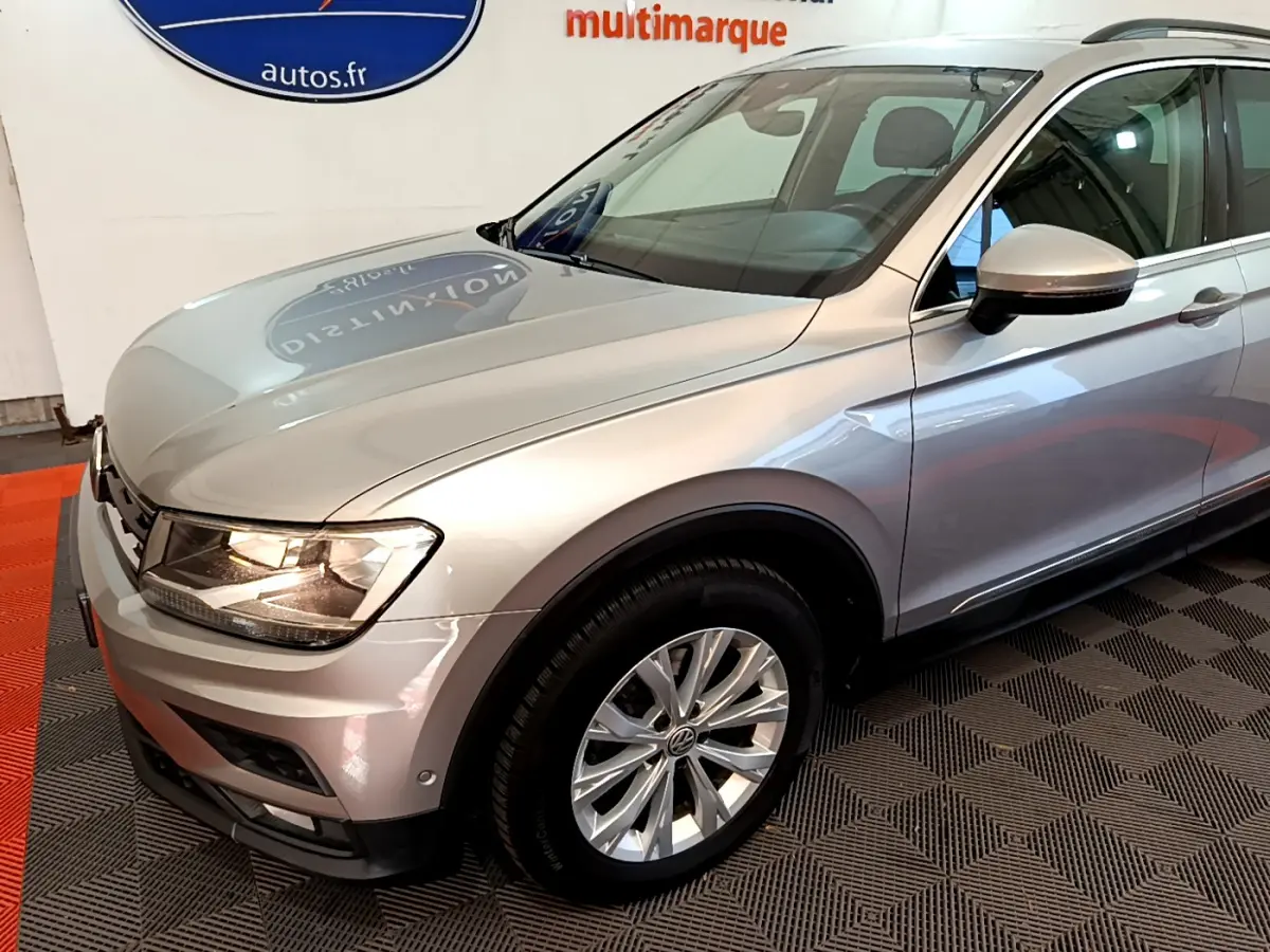 Vue 3/4 avant droit d'un Volkswagen Tiguan gris clair avec jantes alliage et rétroviseurs assortis.