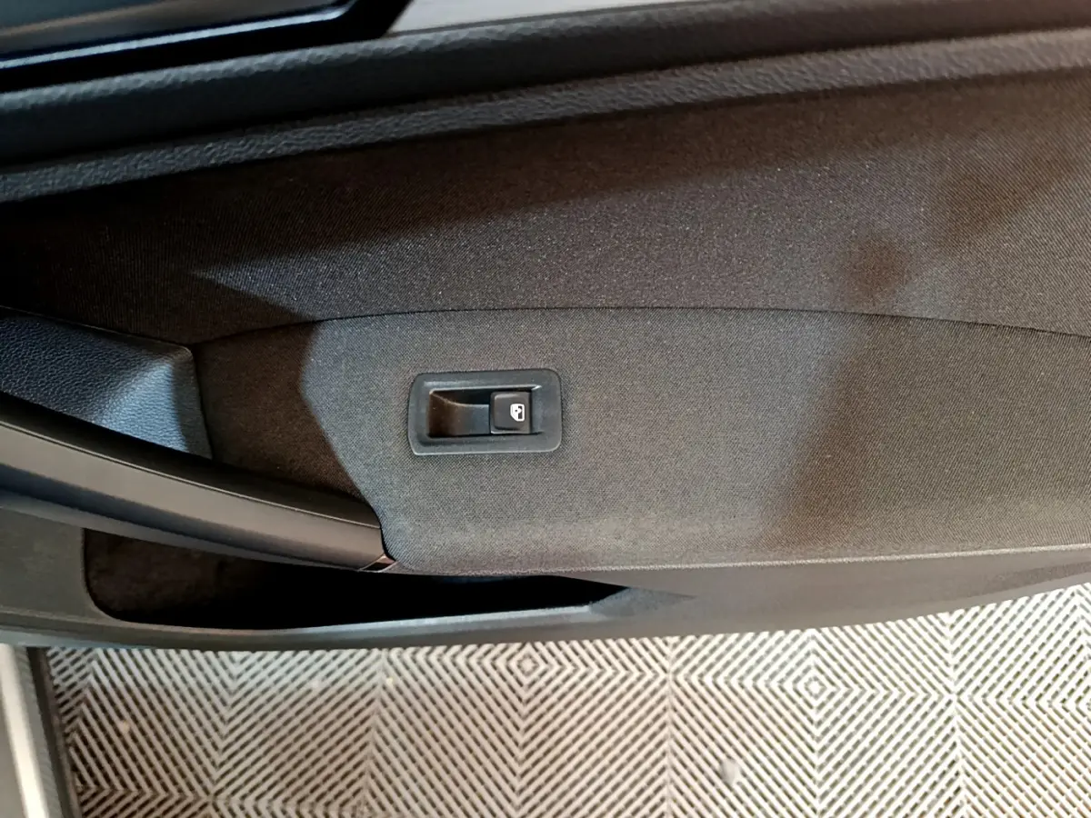 Bouton de verrouillage des portes sur la garniture intérieure noire de la porte côté gauche du Volkswagen Tiguan gris clair.