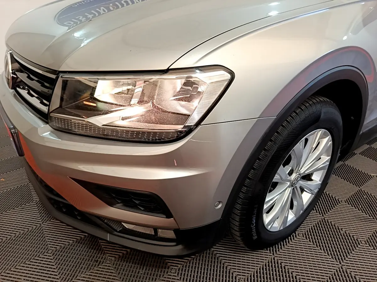 Vue 3/4 avant droit d'un Volkswagen Tiguan gris clair mettant en valeur son phare et sa roue avant.