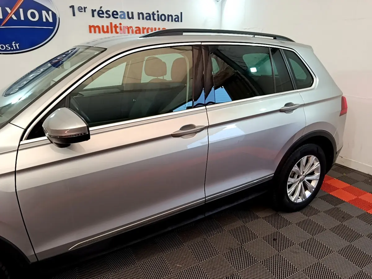 Vue latérale côté gauche d'un Volkswagen Tiguan gris clair 2020 avec rétroviseur et jantes visibles.