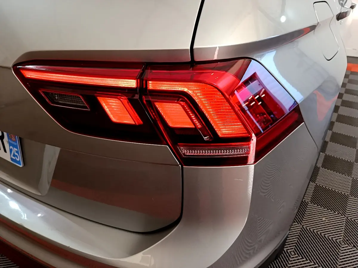 Gros plan sur le feu arrière droit d’un Volkswagen Tiguan gris clair 2020, avec détails lumineux nets et carrosserie brillante.
