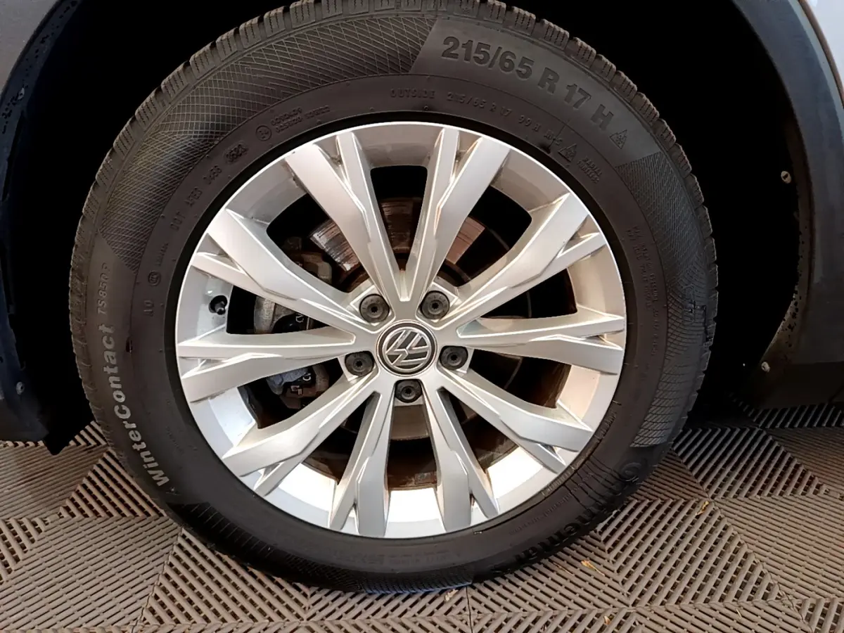 Gros plan sur la jante alliage argentée et pneu hiver du Volkswagen Tiguan gris clair, côté avant droit.