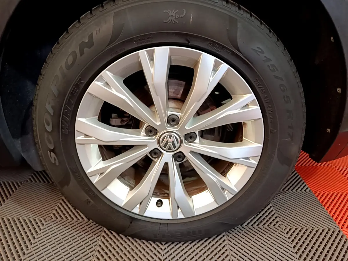 Gros plan sur la roue avant droite du Volkswagen Tiguan gris clair, avec jante alliage et pneu hiver Pirelli.