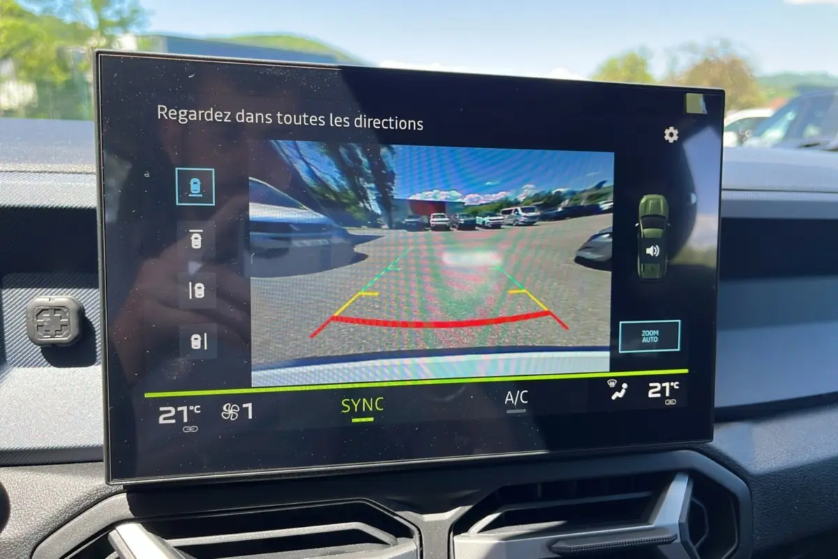 Écran tactile intérieur du Dacia Bigster montrant la caméra multiview en marche avec vue arrière en plein jour.