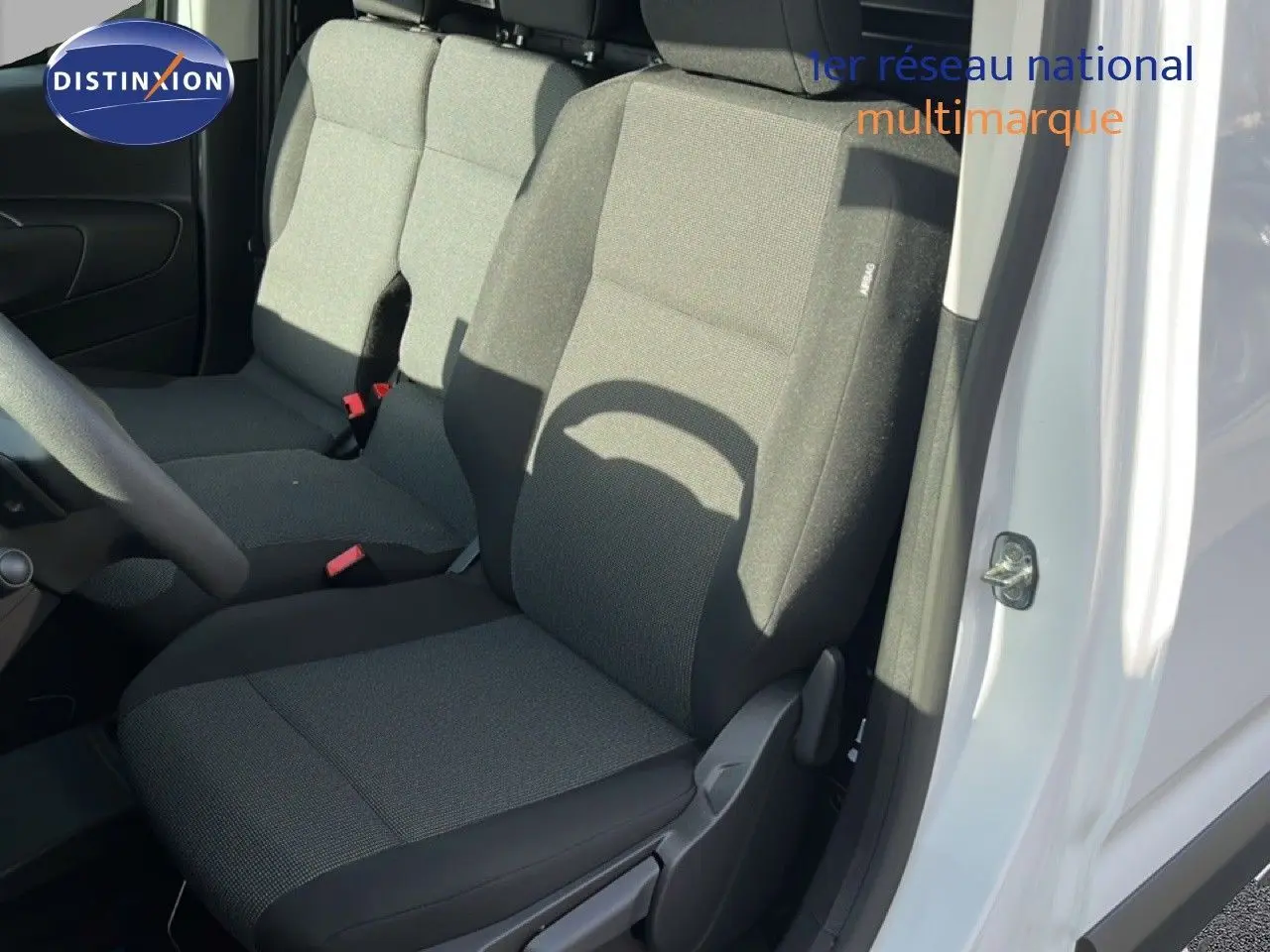 Vue intérieure côté conducteur du Citroën Berlingo blanc Icy 2025, sièges tissu gris foncé avec airbag latéral.