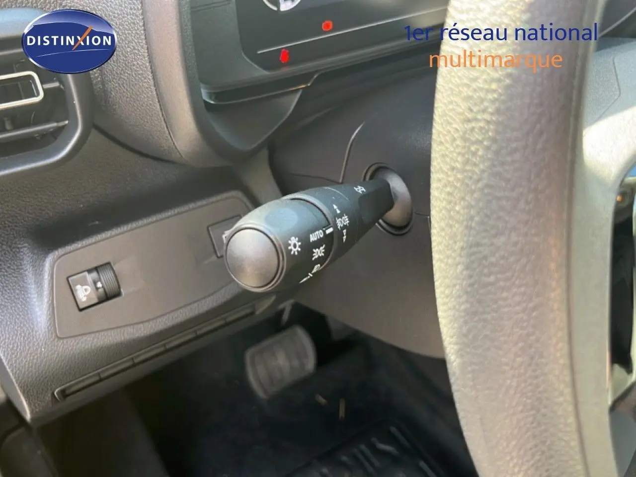 Gros plan sur la commande des phares à gauche du volant dans l’habitacle noir du Citroën Berlingo 2025.