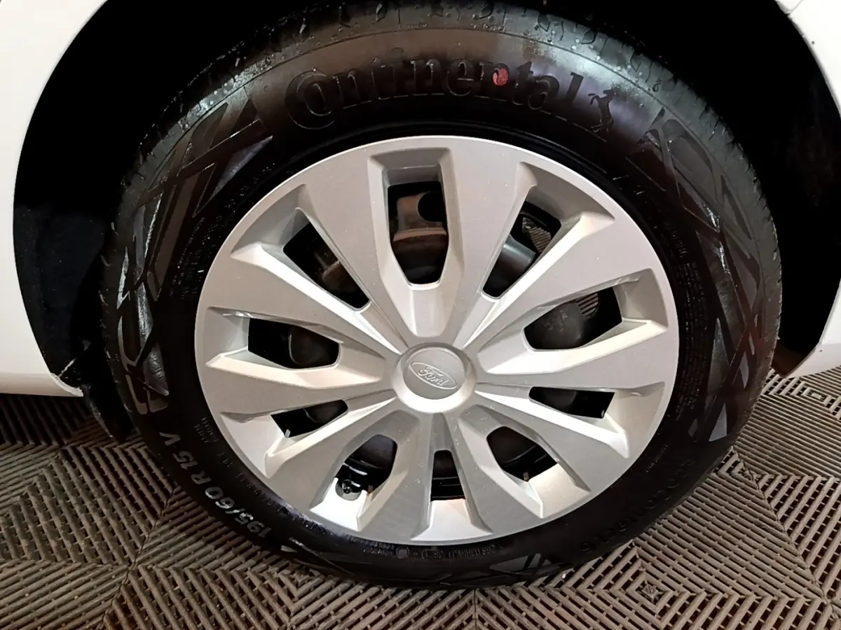 Gros plan sur la roue avant droite d'une Ford Fiesta blanche, avec jante en alliage et pneu Continental visible.