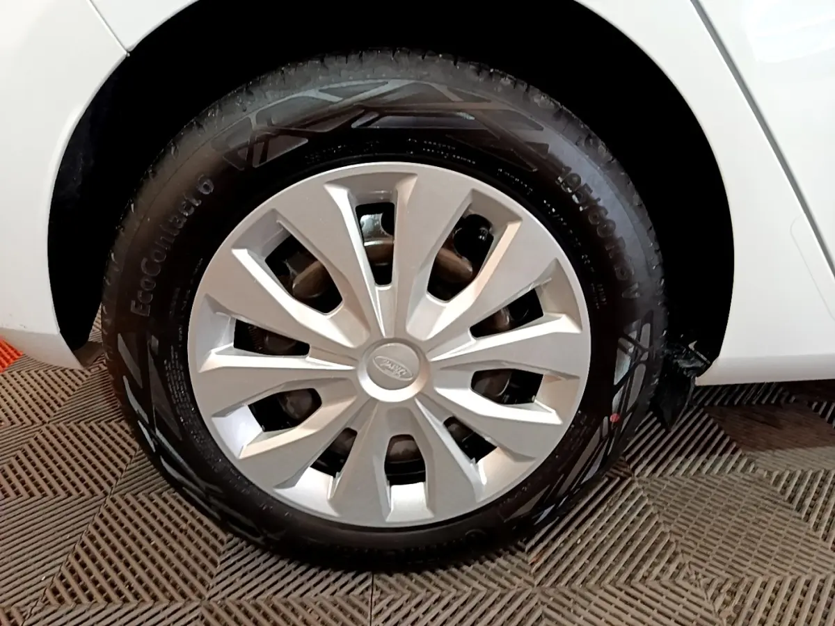 Gros plan sur la roue avant droite d'une Ford Fiesta blanche avec enjoliveur argenté et pneu EcoContact 6.