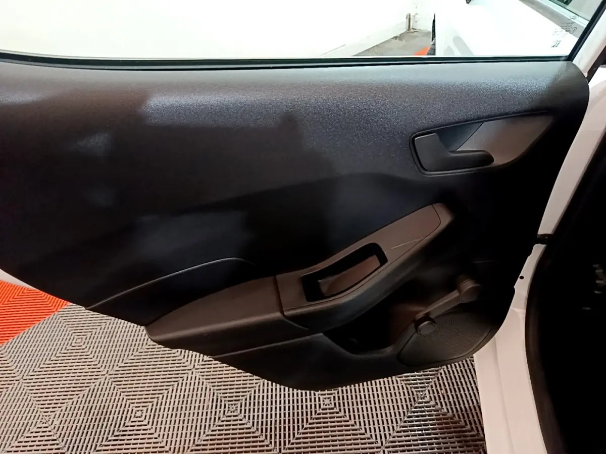 Vue intérieure de la porte avant droite noire d'une Ford Fiesta blanche 2022, avec poignée et commande manuelle de vitre.