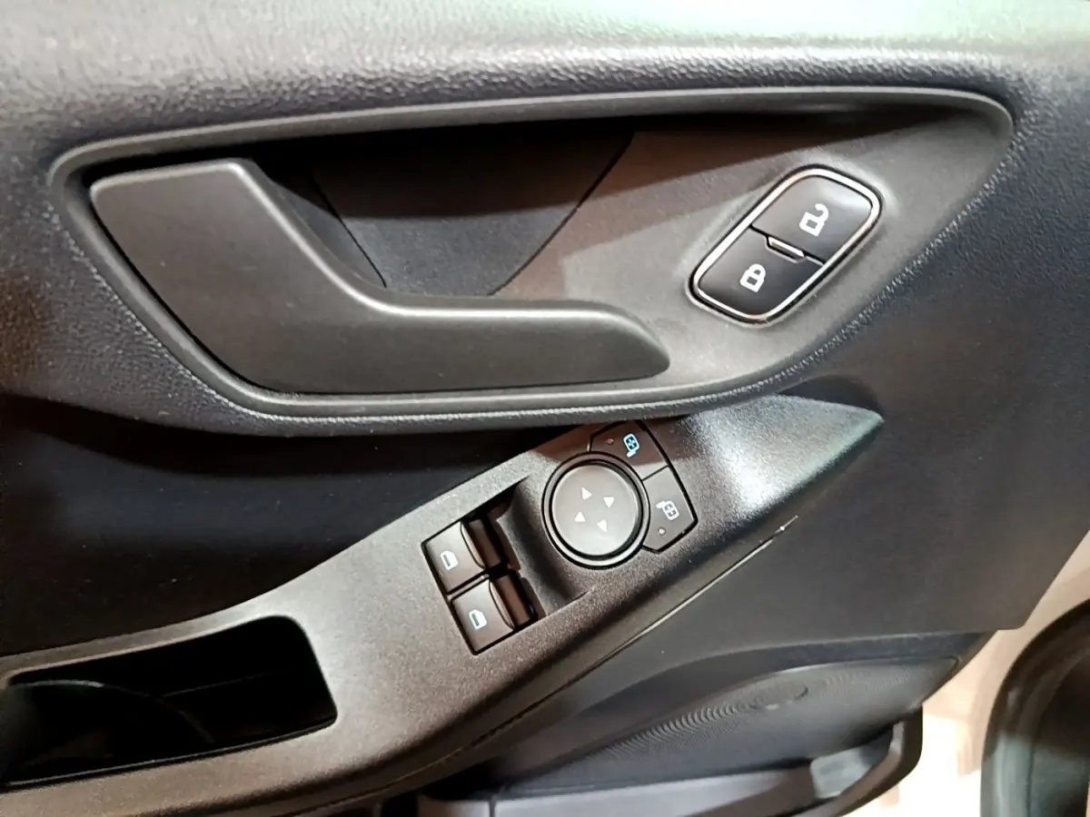 Gros plan sur la porte côté conducteur de la Ford Fiesta blanche, montrant la poignée, les commandes de vitres et de verrouillage.