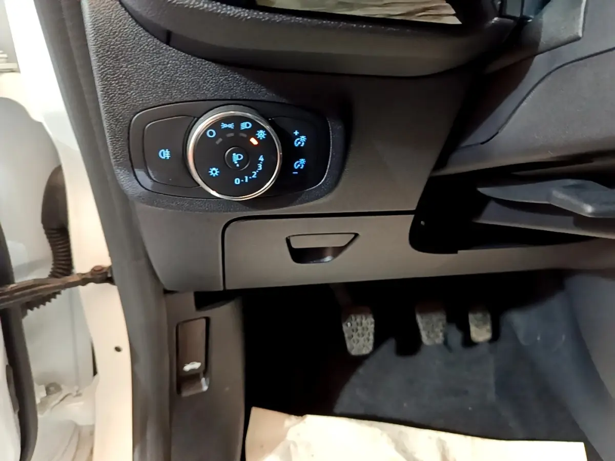 Détail du tableau de bord côté gauche avec commande d’éclairage et pédales dans une Ford Fiesta blanche 2022.