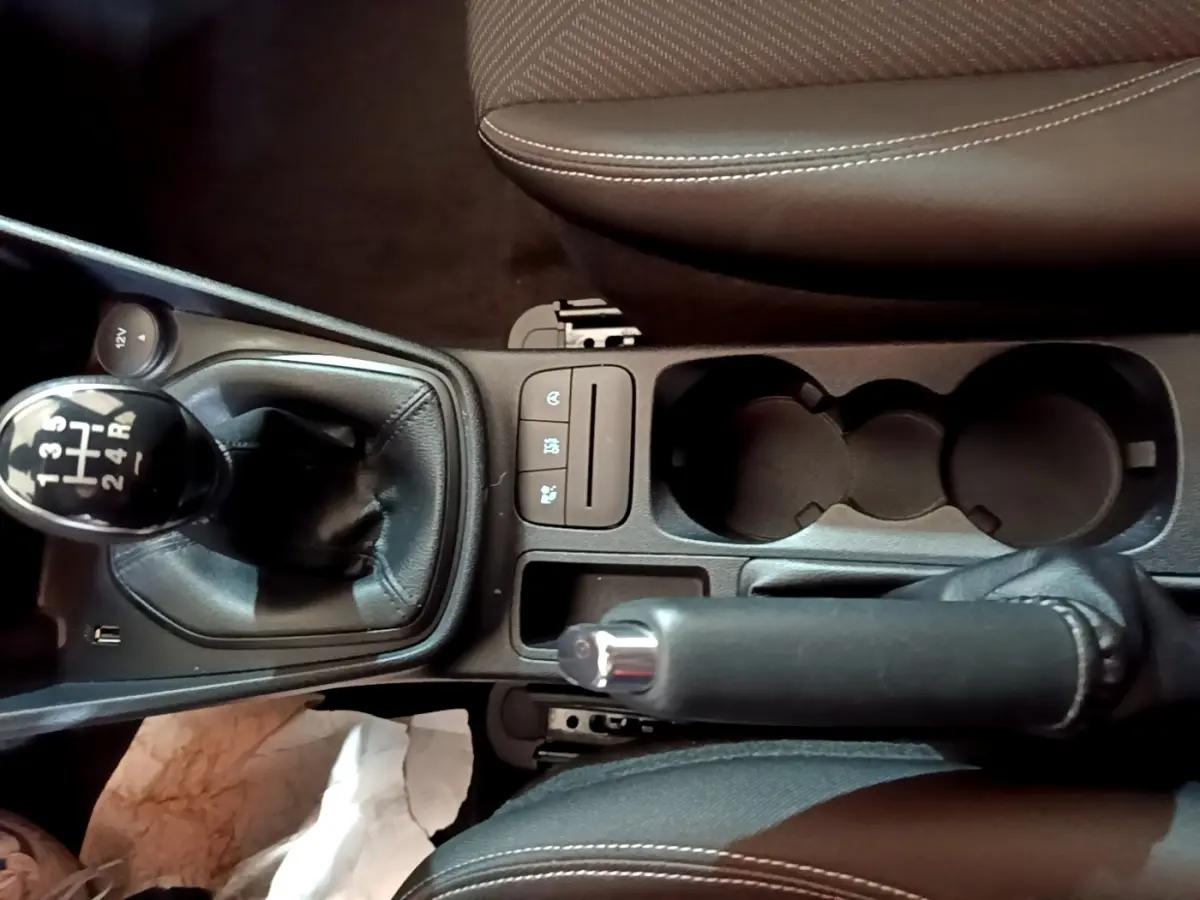 Vue plongeante sur la console centrale noire de la Ford Fiesta blanche, avec levier de vitesse manuel et frein à main.