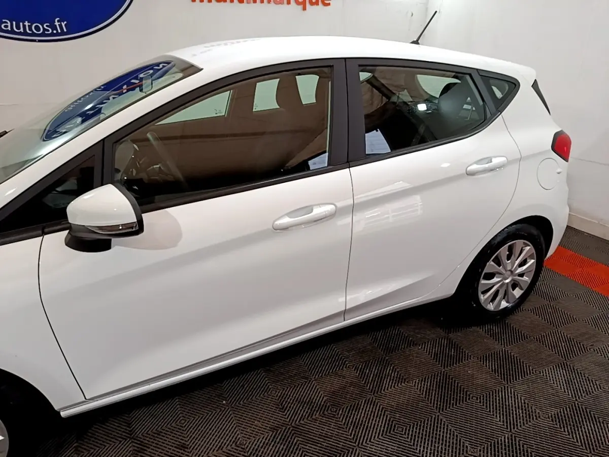 Vue de profil côté gauche d'une Ford Fiesta blanche 2022 avec rétroviseur et poignées assortis.
