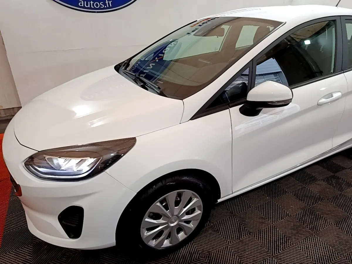 Vue 3/4 avant droit d'une Ford Fiesta blanche 2022 avec phares LED et rétroviseur blanc.