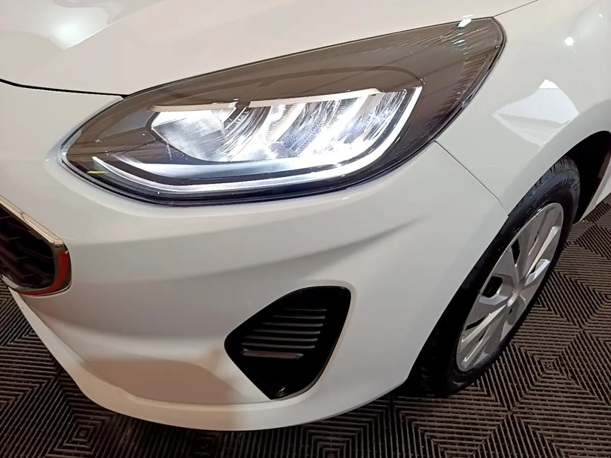 Gros plan sur le phare avant droit blanc d'une Ford Fiesta 2022 avec calandre et jante visibles.