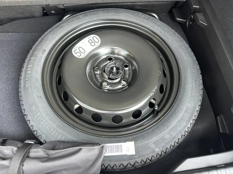 Gros plan sur la roue de secours noire dans le coffre du Renault Captur 1.8 E-Tech hybride 2026, sans couleur carrosserie visible.