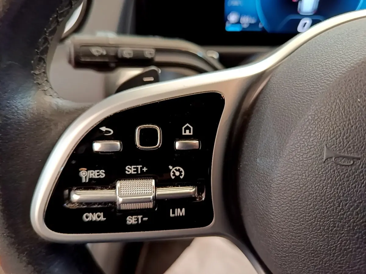 Gros plan sur les commandes multifonctions en alu et noir du volant côté gauche du Mercedes GLB 200 d Business Line gris foncé.