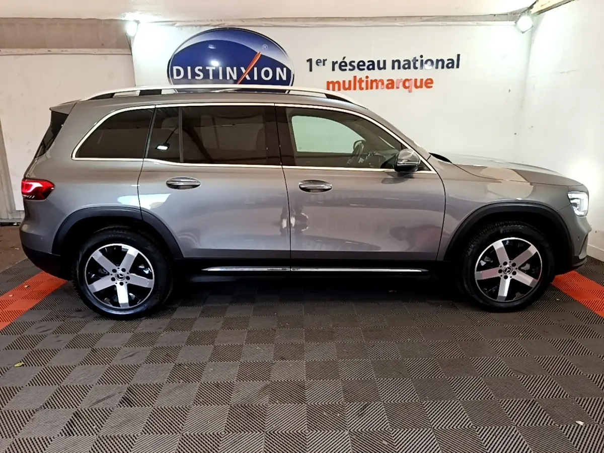 Vue de profil côté droit d’un Mercedes GLB 200 d Business Line gris foncé dans un showroom multimarque.