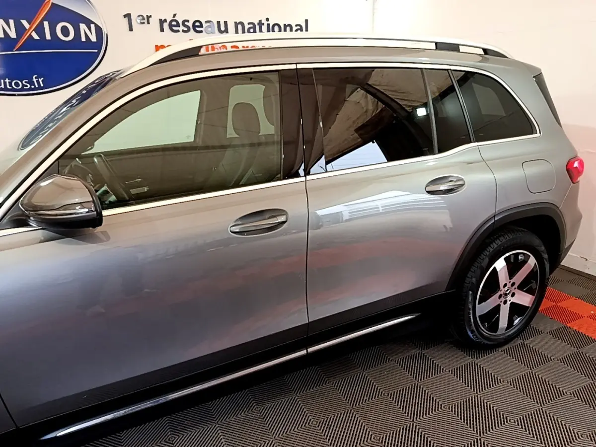 Vue de profil côté gauche du Mercedes GLB 200 d Business Line gris foncé avec jantes alliage et barres de toit chromées.