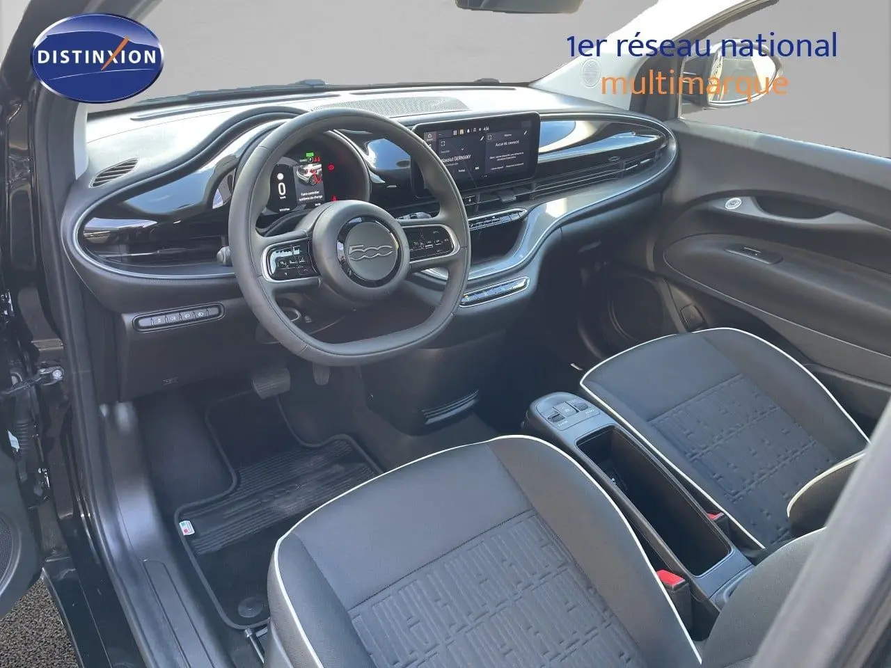 Vue intérieure côté conducteur de la Fiat 500 électrique 2023 noire Onyx, avec tableau de bord numérique et sièges tissu noirs.