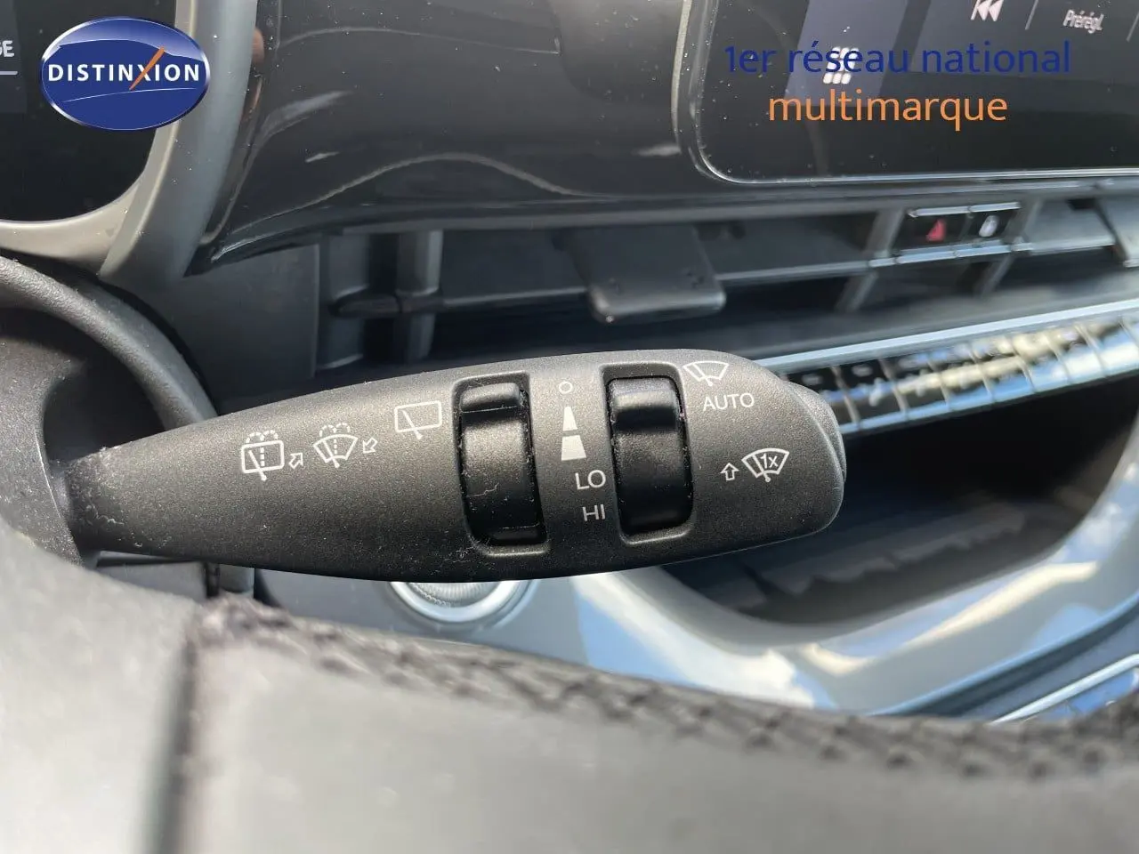Gros plan sur la commande d’essuie-glace à gauche du volant dans l’habitacle noir de la Fiat 500 électrique 2023.
