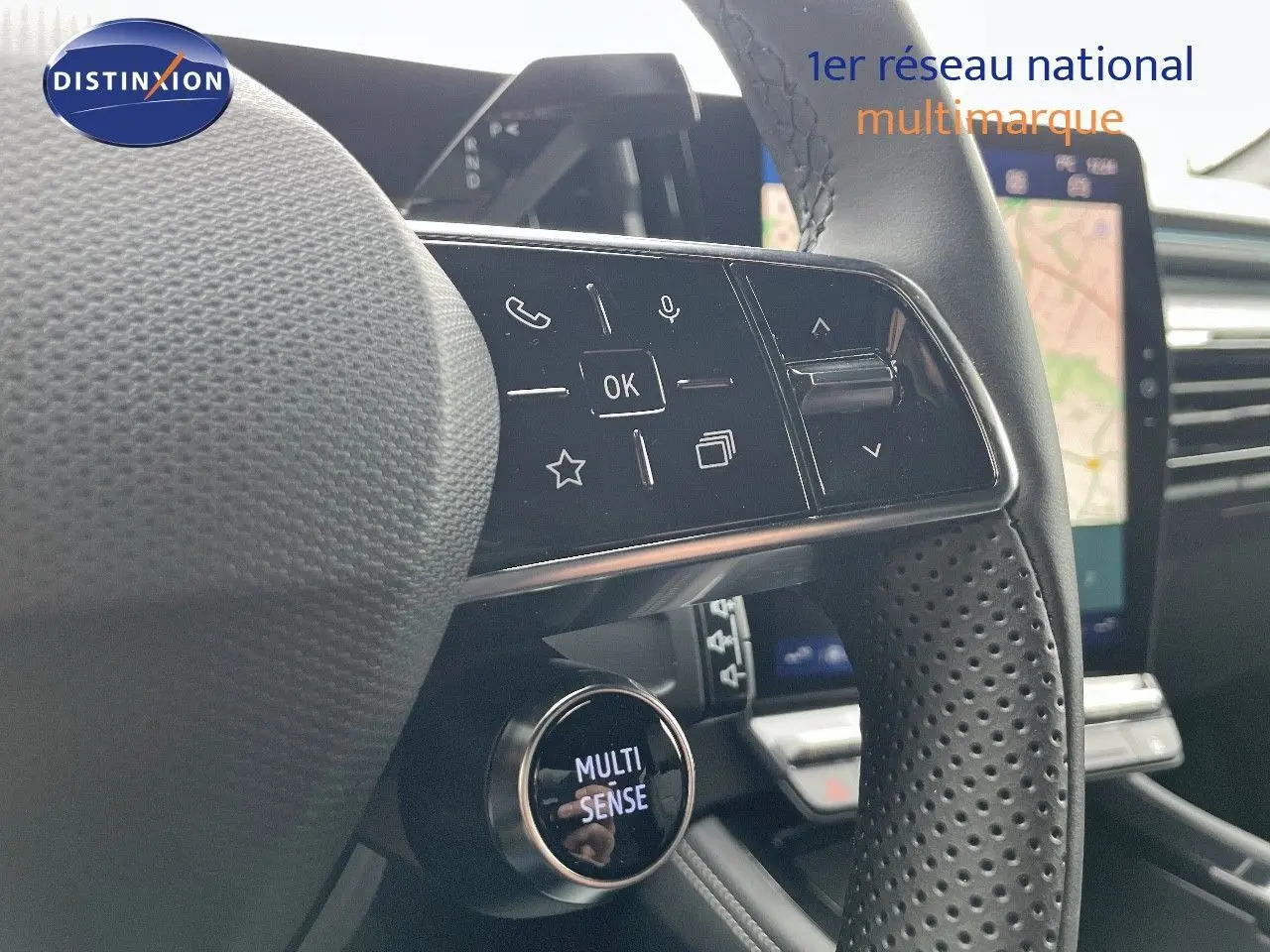Gros plan sur le volant noir perforé du Renault Austral 2025 avec commandes intégrées et bouton Multi-Sense.