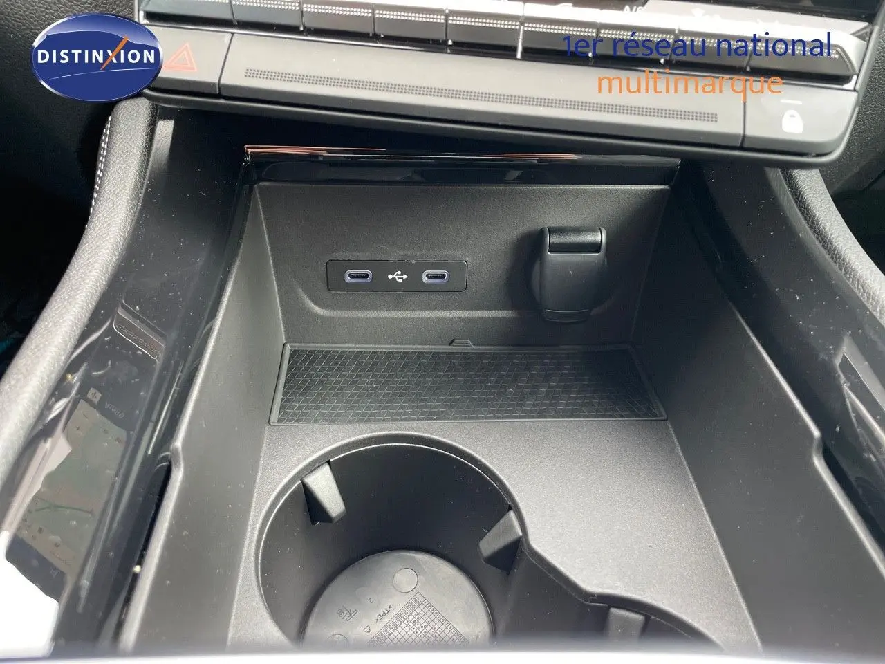 Gros plan sur la console centrale noire du Renault Austral E-Tech 2025, avec ports USB et porte-gobelet intégré.