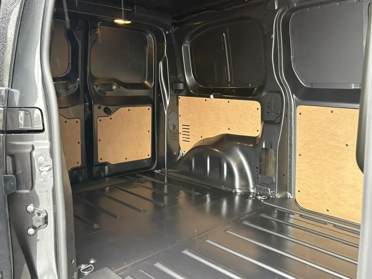 Vue intérieure de la zone de chargement du Citroën Jumpy gris titane, avec panneaux en bois et métal nu.
