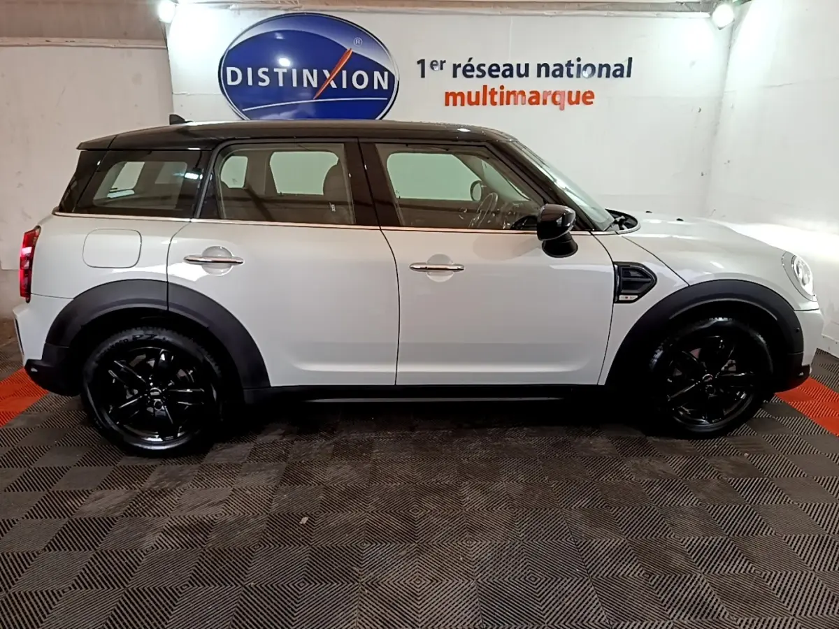 Vue de profil côté gauche d'un MINI Countryman gris clair avec toit noir et jantes noires brillantes.