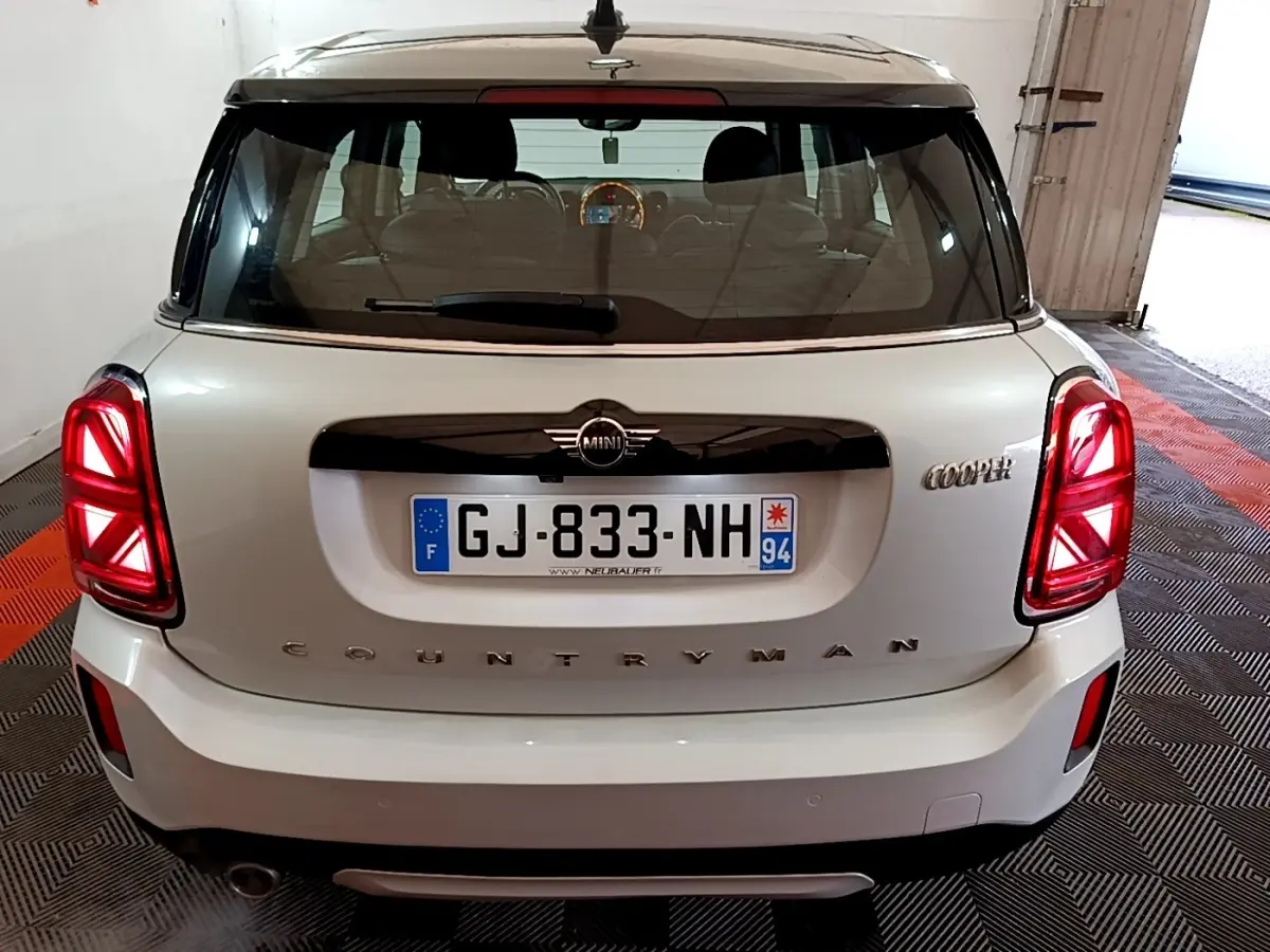 Vue arrière d'une MINI Countryman Cooper gris clair avec feux LED et toit noir dans un garage.